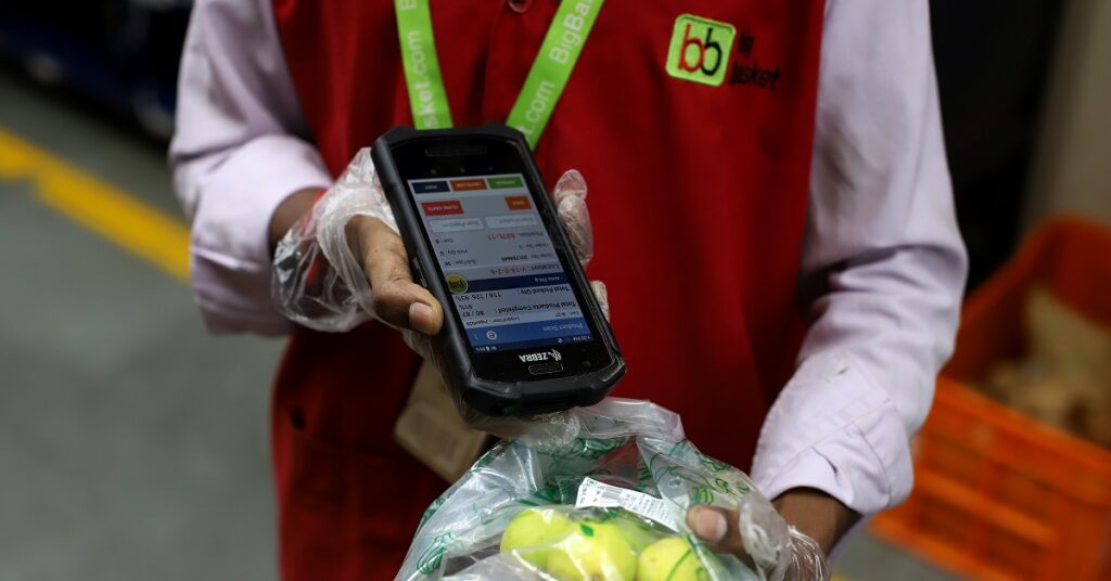 A worker scans a product while fulfilling an order at a BigBasket warehouse in New Delhi, India.